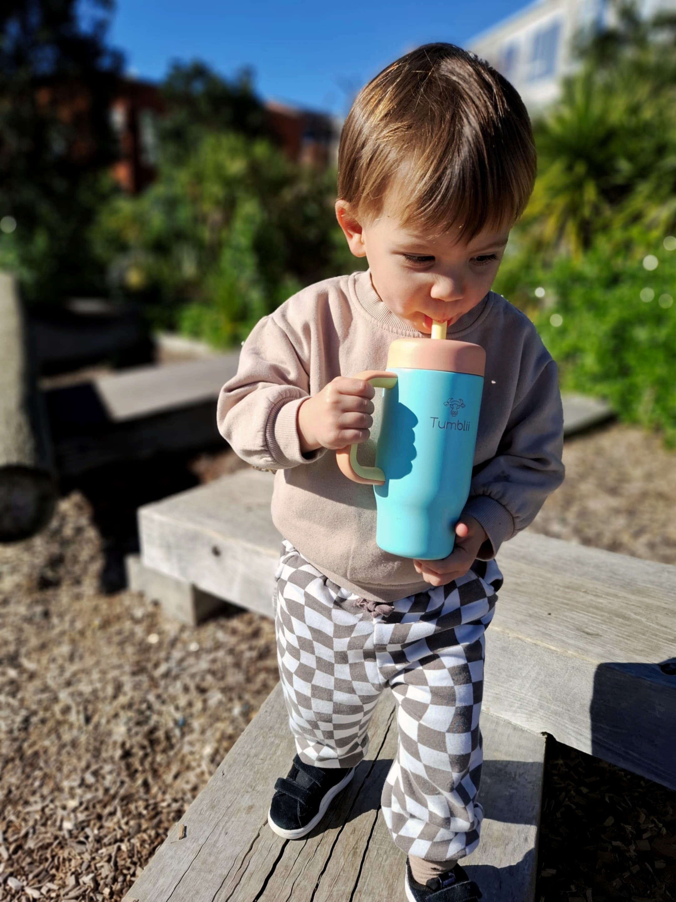 toddler drinking from blue stainless steel tumblii tumbler straw cup outside