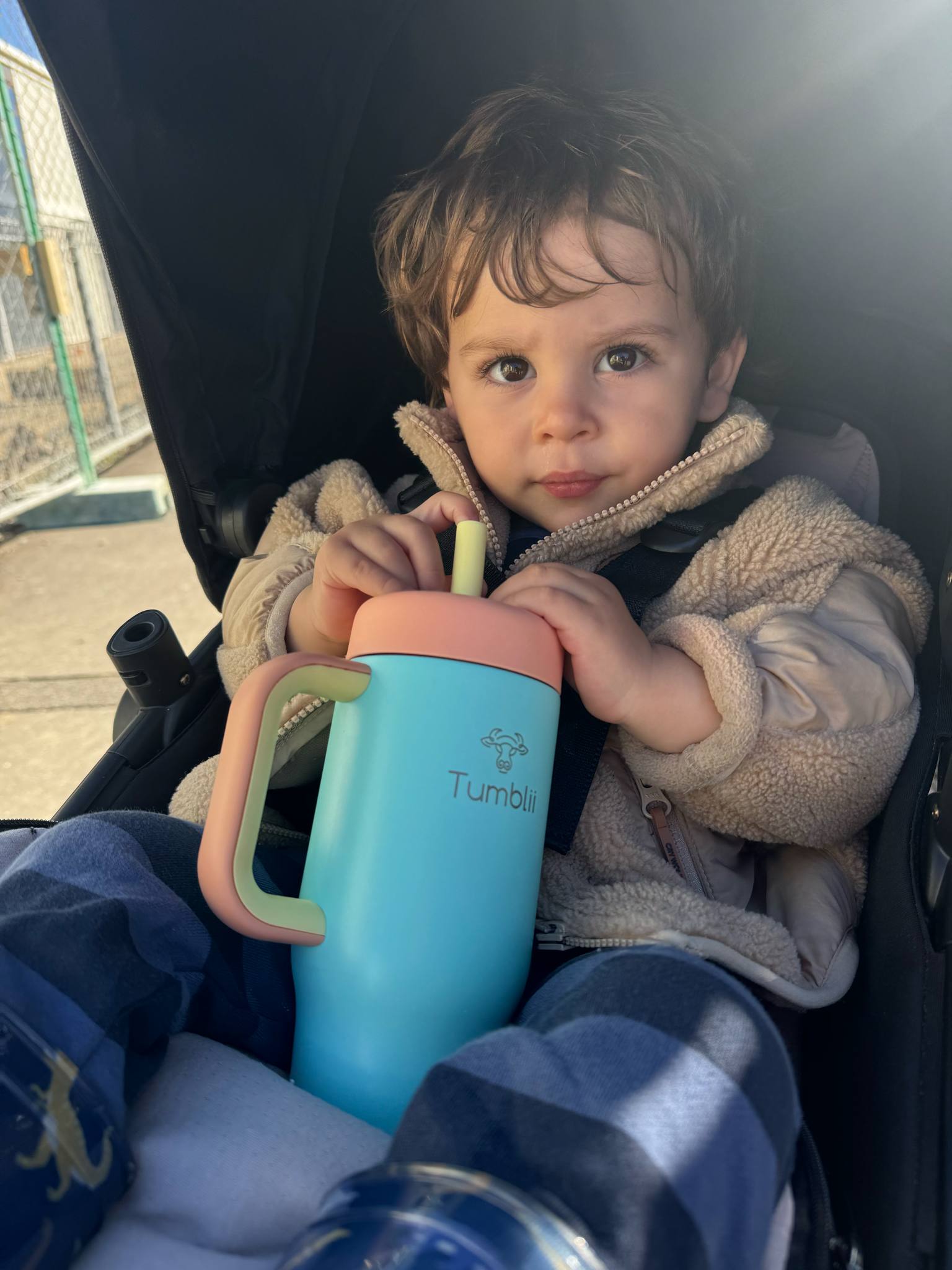 toddler holding blue stainless steel tumblii tumbler in pram
